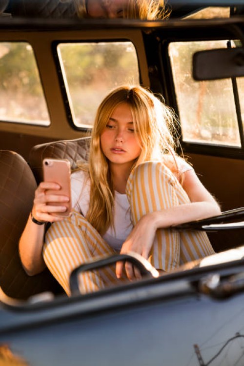 young woman sitting in a van using cell phone - fashion stock pictures, royalty-free photos & images