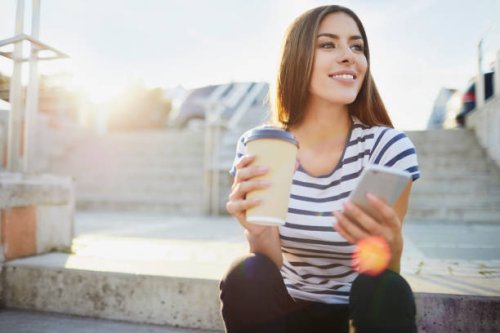 young woman sitting on stairs in the city with phone and coffee - junk food stock pictures, royalty-free photos & images