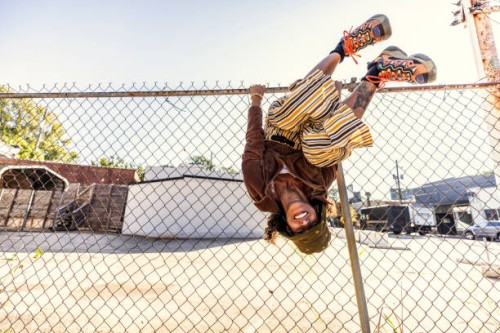 young woman smiling and hanging upside down on fence - fashion photos et images de collection