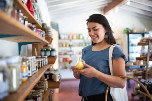 young woman smiling buying healthy, artisanal food at small local store - food stock pictures, royalty-free photos & images