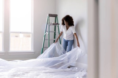 young woman spreads drop cloth on floor - home decoration stock pictures, royalty-free photos & images