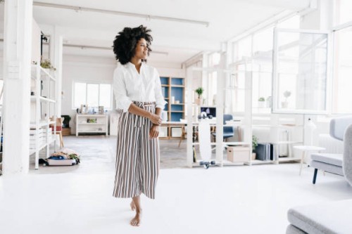 young woman standing in her apartment, looking confident - fashion stock-fotos und bilder