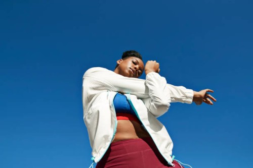 young woman stretching arm against clear blue sky on sunny day - fashion stock pictures, royalty-free photos & images
