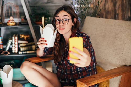 young woman taking a selfie with her chinese takeaways. - junk food stock pictures, royalty-free photos & images