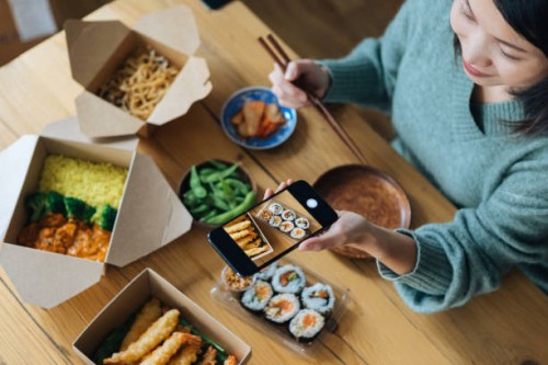 young woman taking photo with smartphone while eat takeaway food at home - junk food stock pictures, royalty-free photos & images
