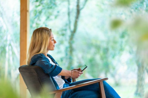 young woman using digital tablet while sitting on armchair at front yard - garden decoration photos et images de collection