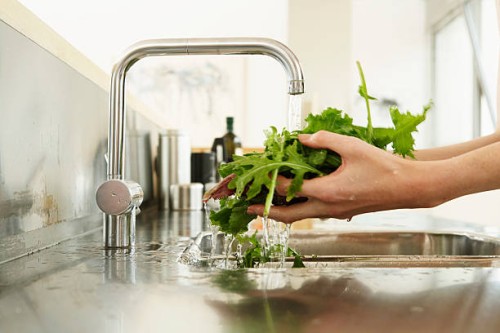 young woman washing lettuce at kitchen sink, close-up of hands - food stockfoto's en -beelden