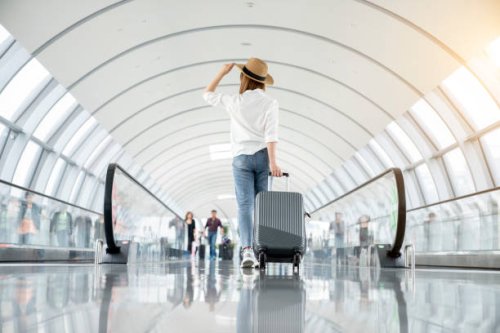 young woman wearing casual clothes and walking in the airport hall - travel photos et images de collection