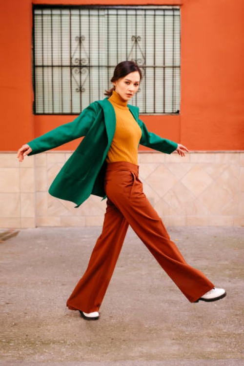 young woman wearing green jacket walking on footpath against building in city - fashion stock pictures, royalty-free photos & images