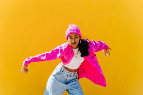 young woman wearing knit hat dancing in front of yellow wall - fashion stock pictures, royalty-free photos & images