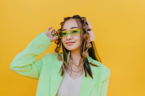 young woman wearing sunglasses and listening music through headphones in studio - fashion stock-fotos und bilder