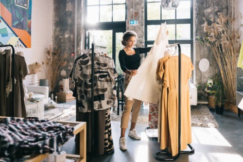 young woman with a keen eye for fashion, browsing through a curated collection of dresses - fashion stock pictures, royalty-free photos & images