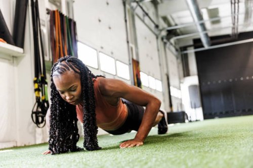 young woman with braided hair doing push-ups at gym - hairstyle stockfoto's en -beelden
