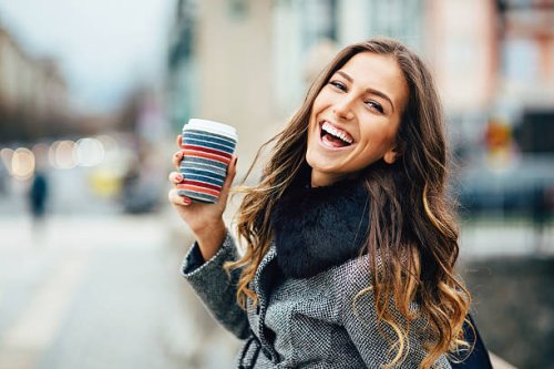 young woman with coffee cup smiling outdoors - coffee stockfoto's en -beelden