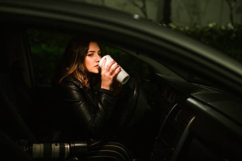 young woman with disposable cup and camera in a car at night - junk food stock pictures, royalty-free photos & images