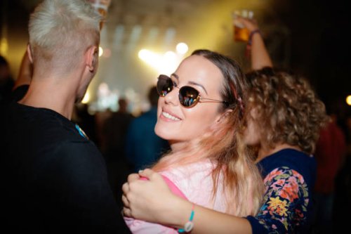 young woman with friends on live event, looking at camera over shoulder - concert stock pictures, royalty-free photos & images