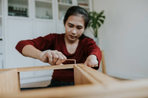 young woman with hand disability installing a wooden shelf by herself. - home decoration stock pictures, royalty-free photos & images