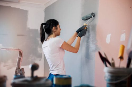 young woman with hearing aid painting walls - home decoration stock pictures, royalty-free photos & images