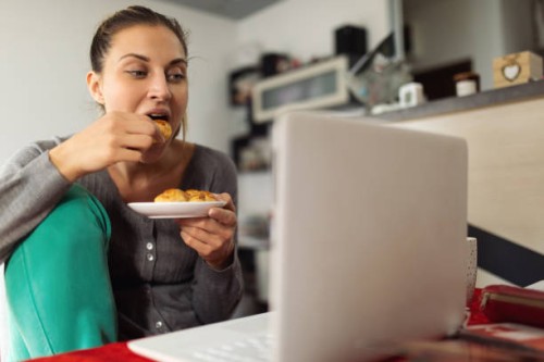 young woman working and eating at home office - junk food stock pictures, royalty-free photos & images
