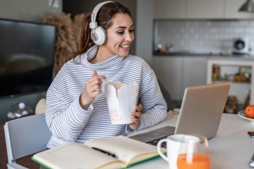 young woman working from home and eating pasta - junk food stock pictures, royalty-free photos & images