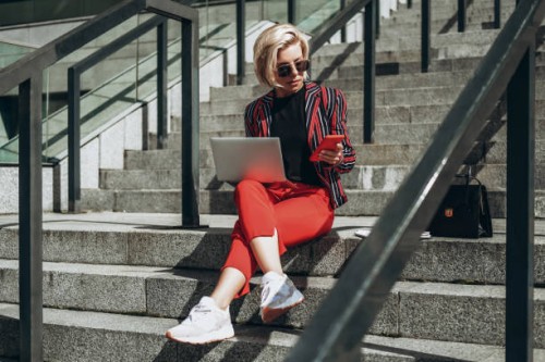 young woman working on laptop sitting on stairs. - fashion stock pictures, royalty-free photos & images