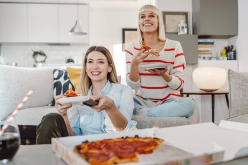 young women watching favorite tv show and eating pizza - junk food stock pictures, royalty-free photos & images