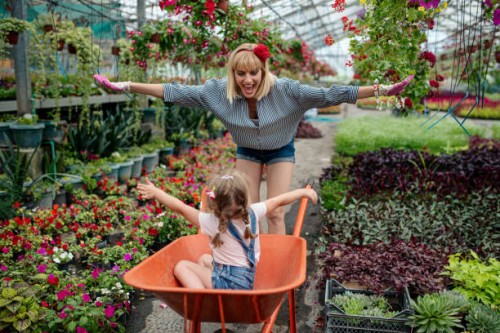young women working together with their little daughter in a flower garden showing her family business - garden decoration stock pictures, royalty-free photos & images