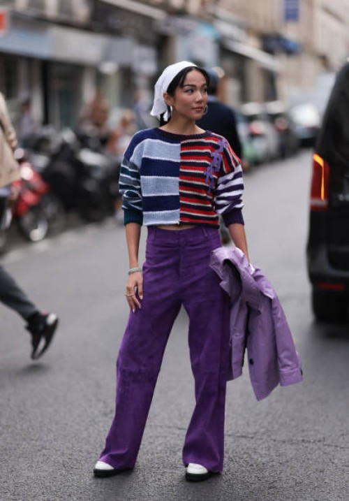 Yoyo Cao is seen outside Dries Van Noten show wearing white head piece, silver hoop earrings, blue, lilac and red striped sweater, lilac colored pair...