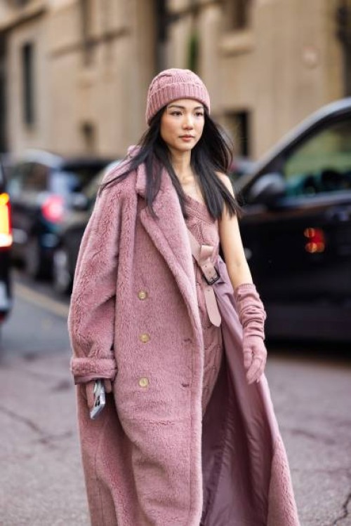 Yoyo Cao is seen wearing a pink hat, a matching pink long dress with a cross-body trail and a pink teddy long coat outside the Max Mara show during...