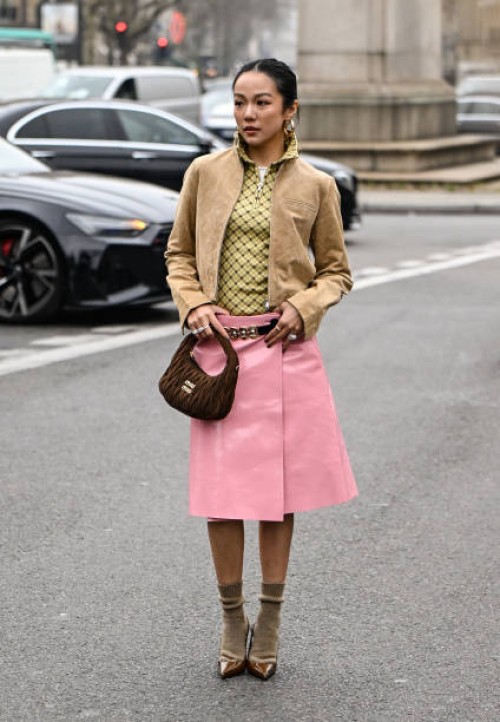 Yoyo Cao is seen wearing a tan Miu Miu jacket, plaid shirt, pink Miu Miu skirt, brown Miu Miu bag and brown heels with tan socks outside the Miu Miu...
