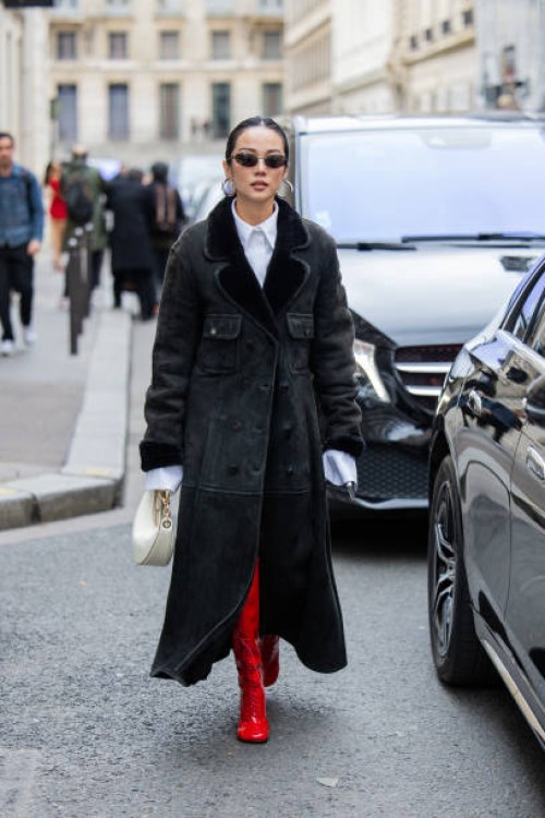 Yoyo Cao wears creme white bag, shearling black coat, white button shirt, red boots outside Valentino during the Womenswear Fall/Winter 2024/2025 as...