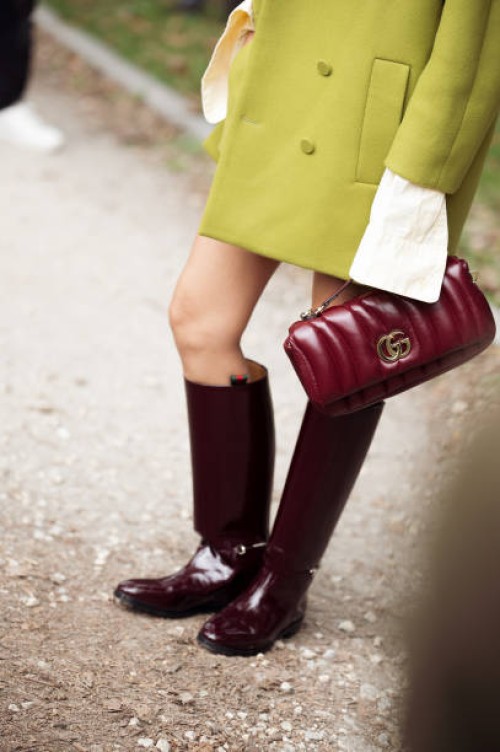 Yoyo Cao wears green mini shorts, white top, green beanie or a hat, green coat, burgundy boots, burgundy bag outside Gucci show during the Milan...