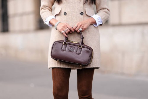 Yoyo Cao wears silver rings, shiny dark brown Miu Miu leather bag, outside Miu Miu, during the Paris Fashion Week Spring/Summer 2025 on October 1,...