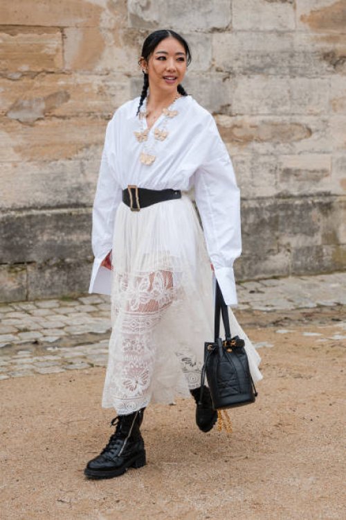 Yuwei Zhangzou wears white shirt, cream lace maxi skirt, black belt, black Dior bag, black boots, outside Dior, during the Womenswear Fall/Winter...