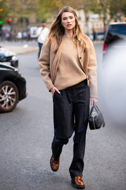 Zita d'Hauteville wears a beige Miu Miu sweater with matching cardigan, black trousers and black Miu Miu bag, outside Miu Miu, during the Womenswear...